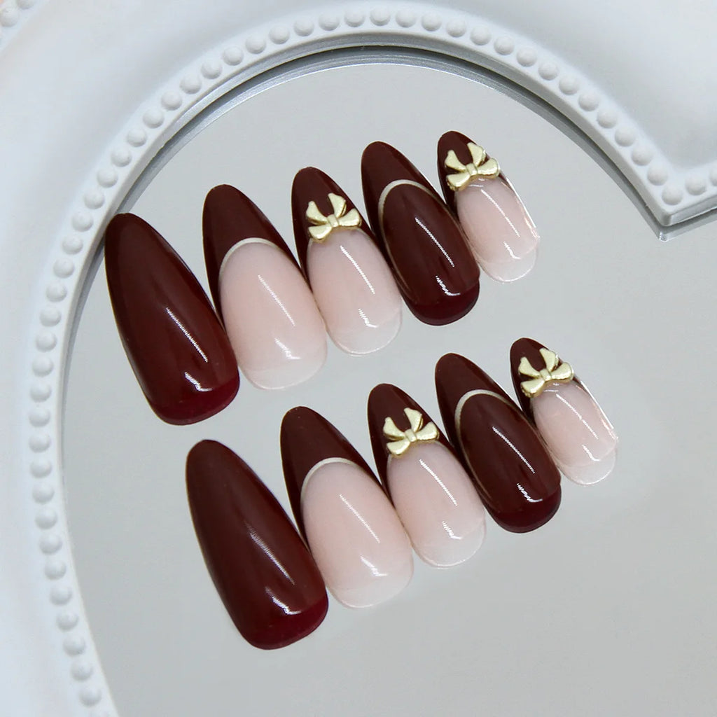 24 handmade almond nails. Burgundy base with nude French, white lines & metal bows. Reusable, elegant retro style for daily wear